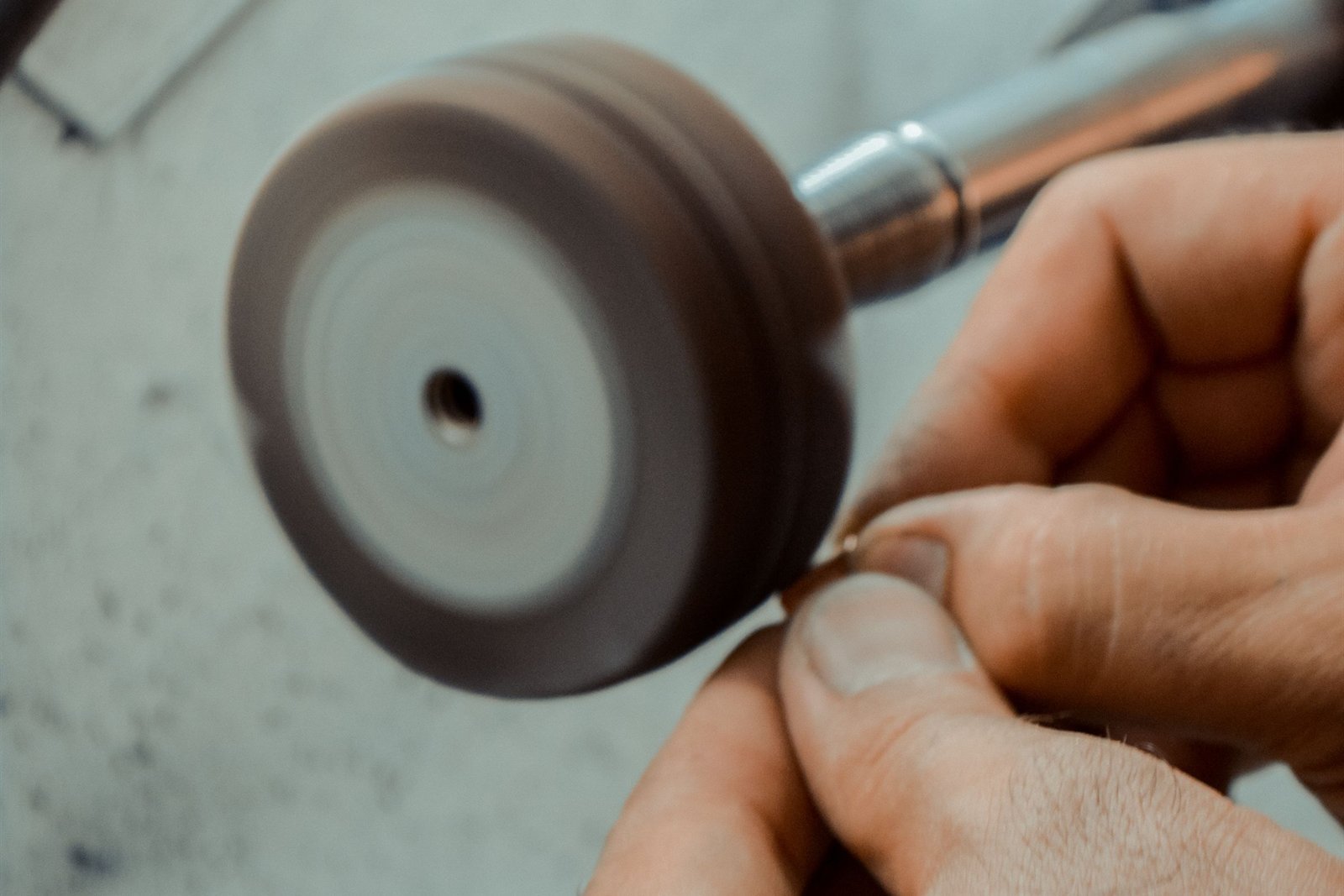 A felt bob spinning on a handpiece while a small metal part is held against it
